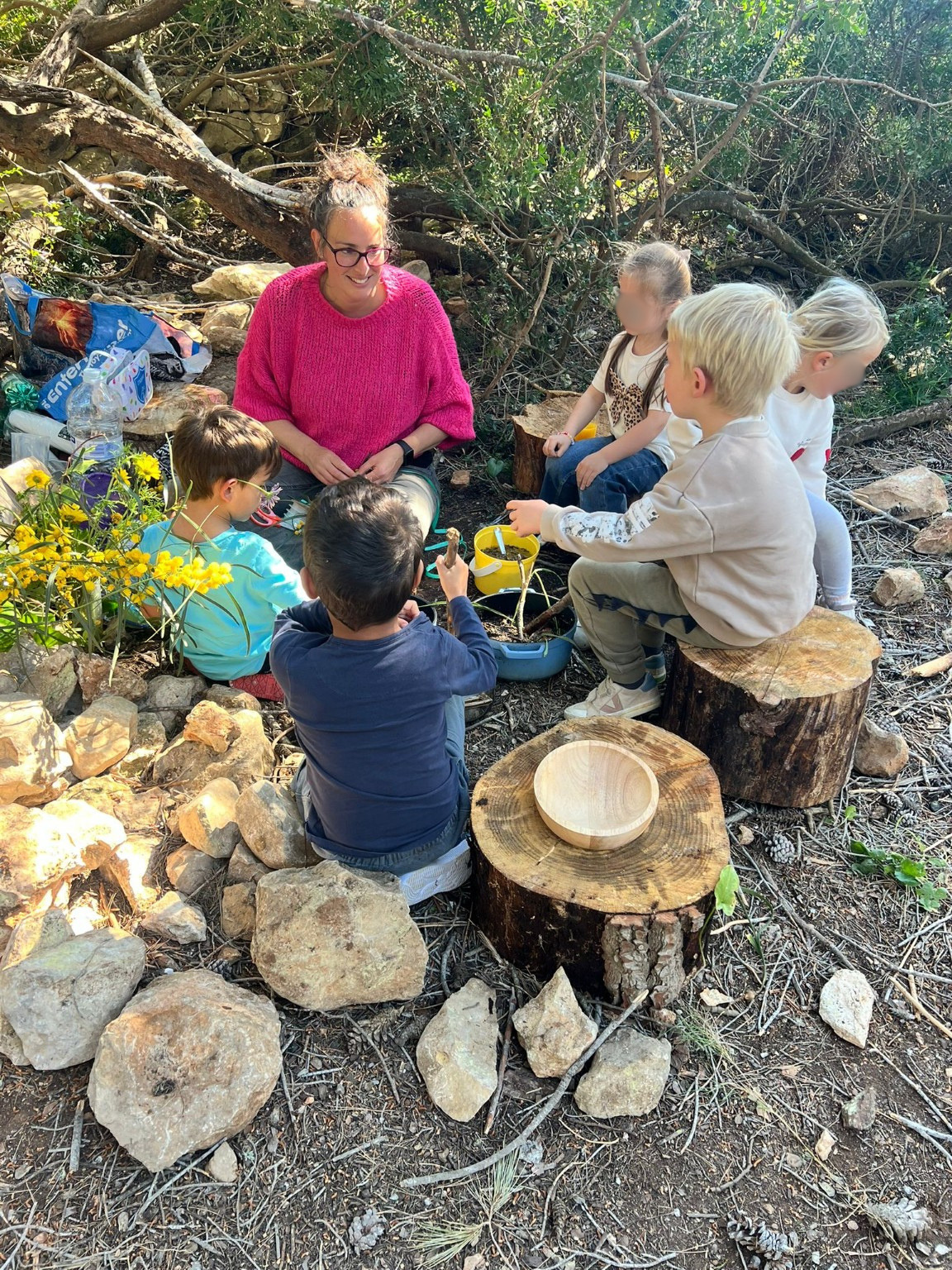 Ellen zit met een groepje kinderen in de natuur. 